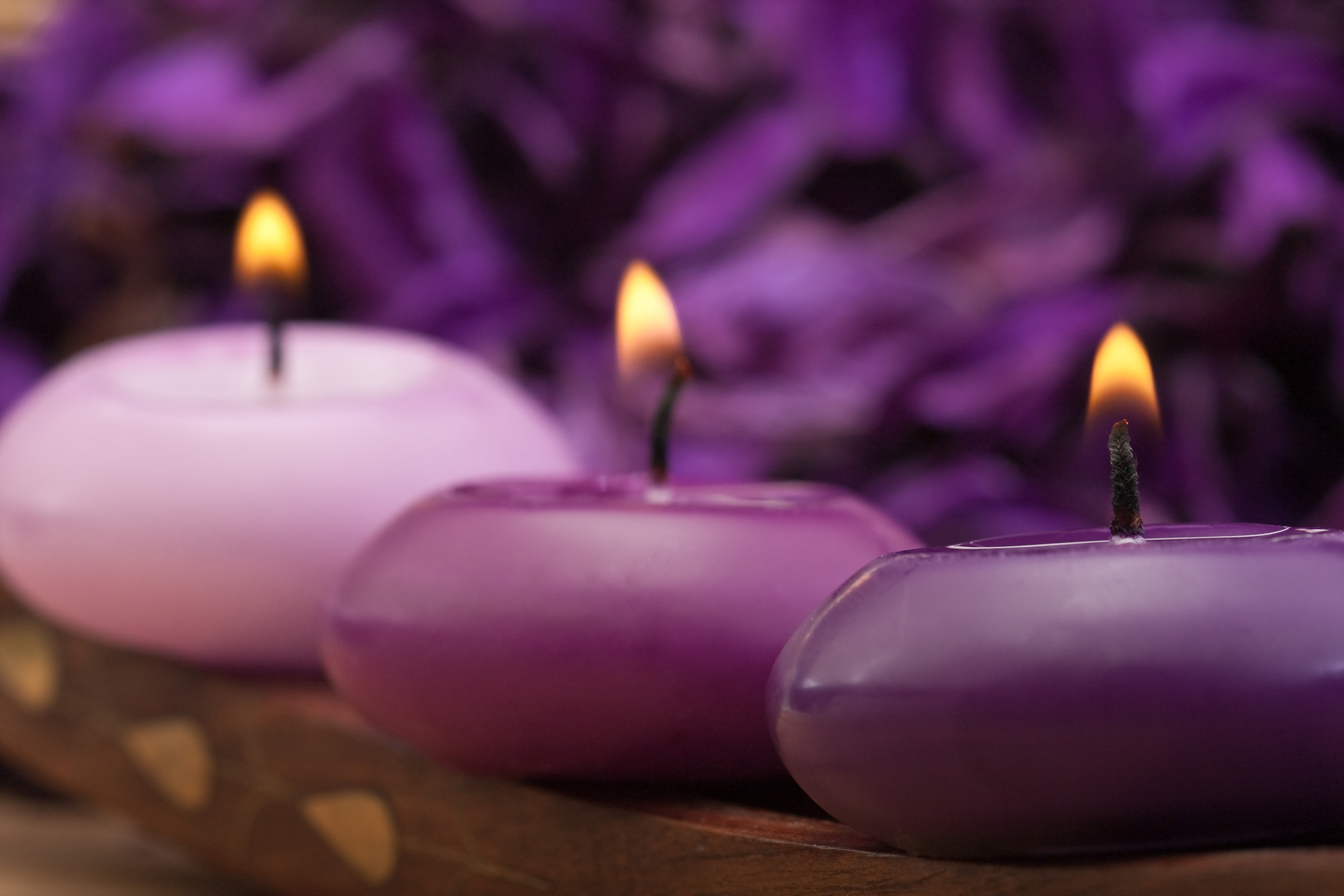 three lite candles in shades of purple